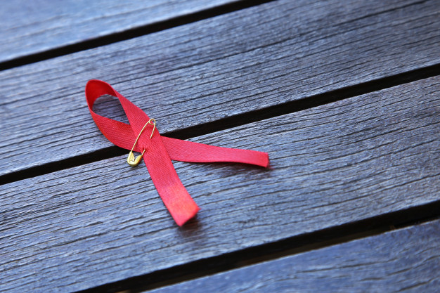 cancer-awareness-red-ribbon-wooden-surface_181624-8809